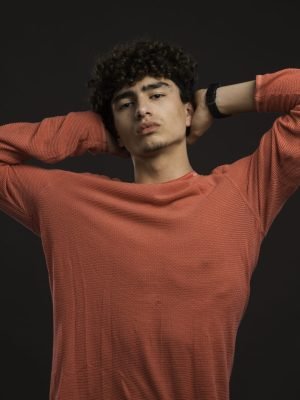 Young model with curly hairs holding his head. High quality photo